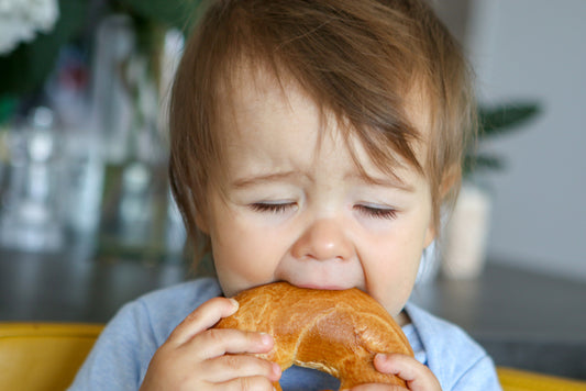 a small child eating a bread roll leaky gut gluten celiac disease relief